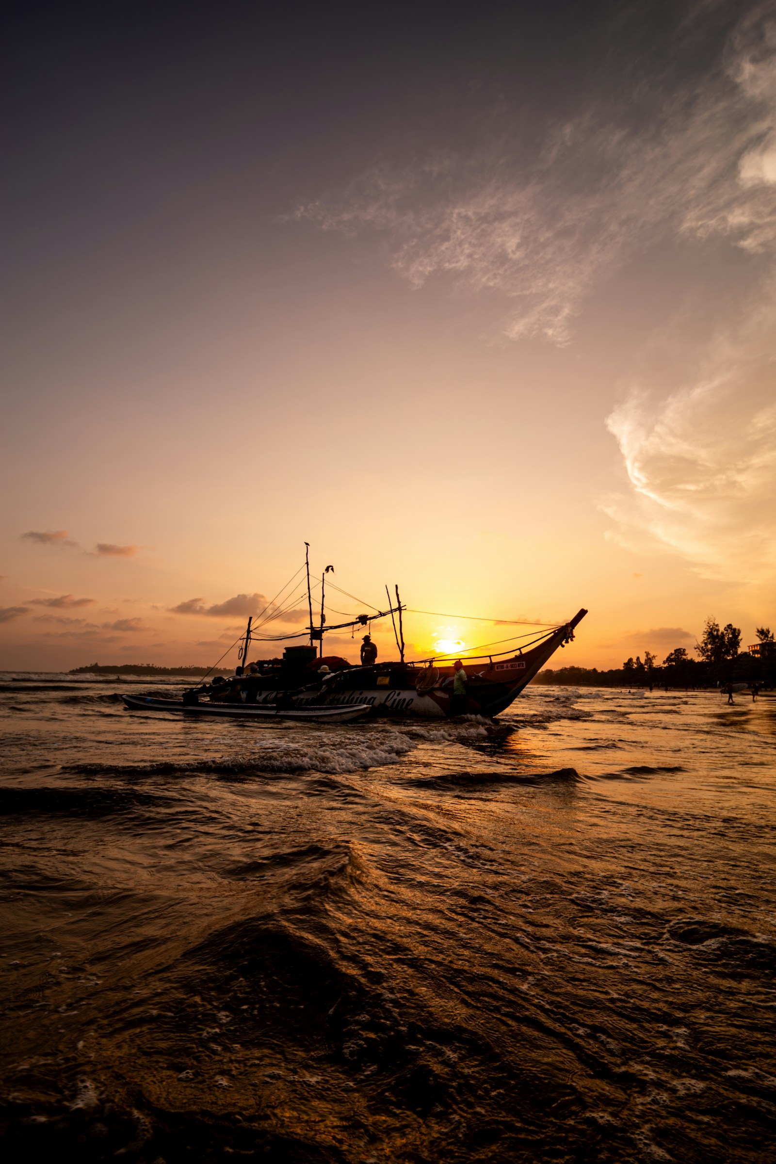 Traditional fishing boat returning to Weligama Beach at sunset